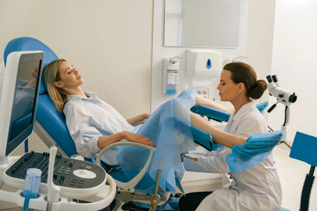 Patiente installée sur un fauteuil gynécologique pendant un examen, la gynécologue à ses côtés